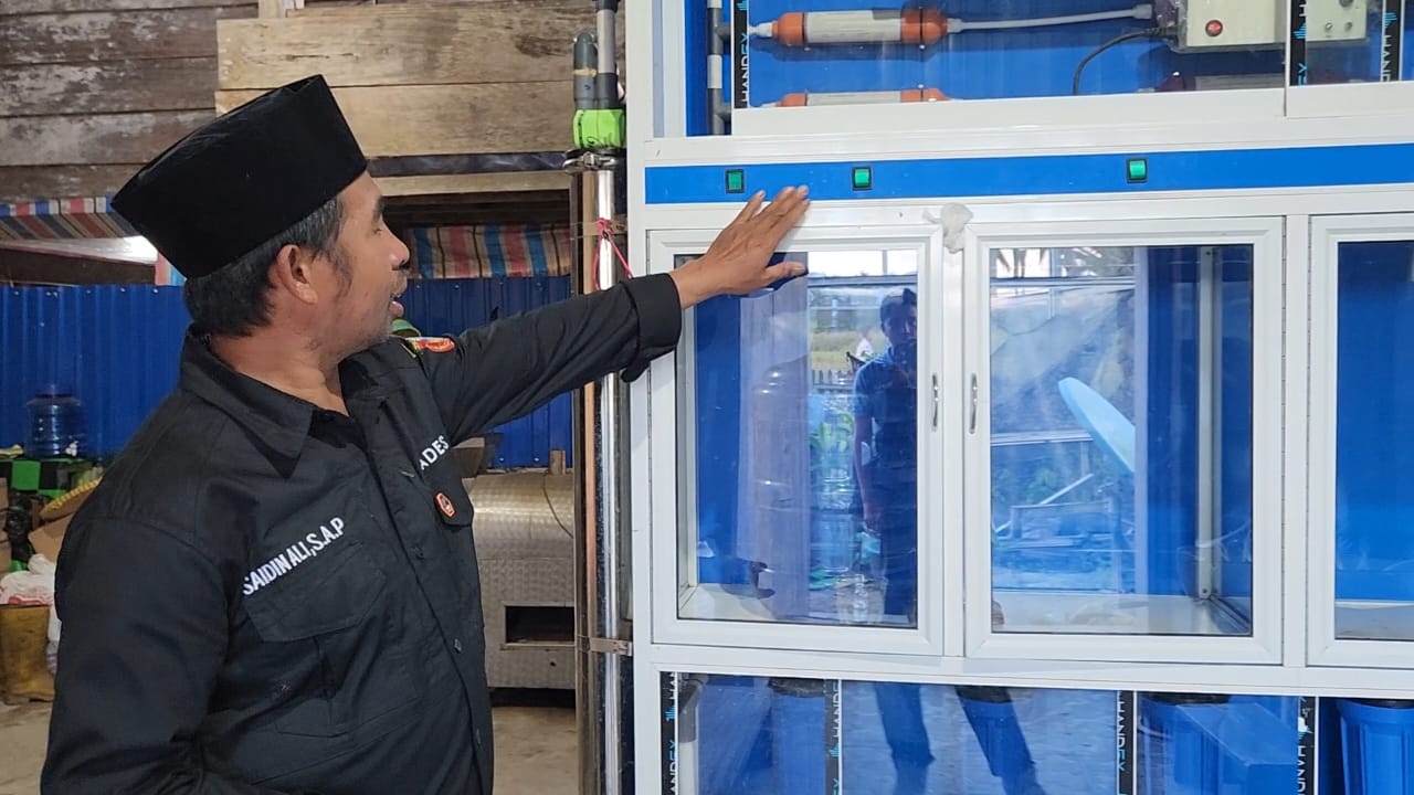 Saidin Ali, warga Desa Olu yang mengelola usaha depot air minum, kini dapat mengoperasikan seluruh mesin produksinya secara bersamaan sejak listrik PLN hadir 24 jam penuh. Foto : Ist